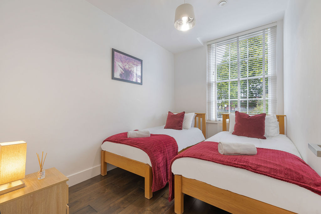 Twin bedroom with red throws in the three bedroom Reading apartment