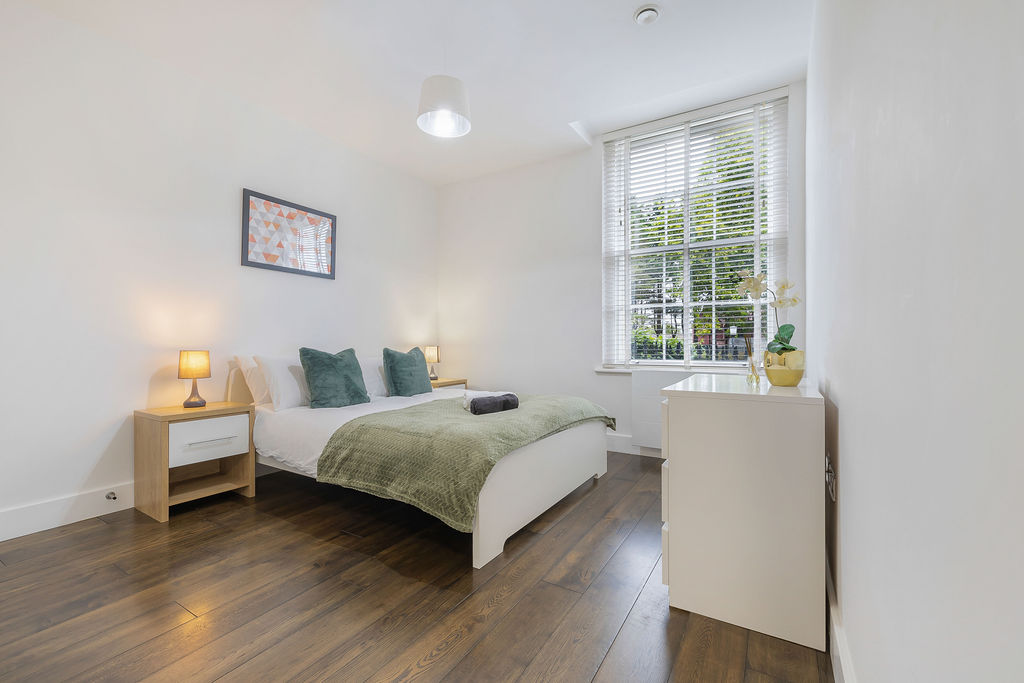 Main bedroom with a green throw in the three bedroom Reading apartment
